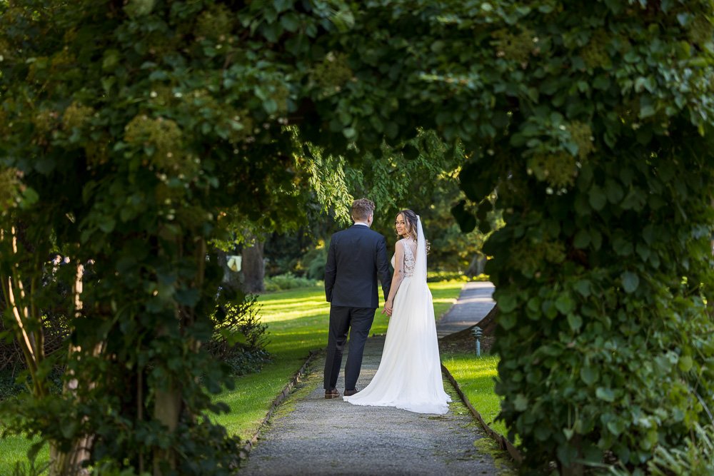 Newlywed couple strolls through the grounds of Bailey Arboretum.