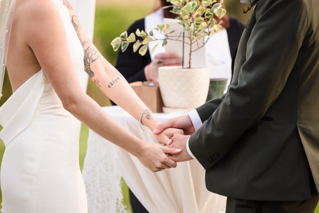 bride and groom holding hands at outdoor ceremony at Mansion at West Sayville