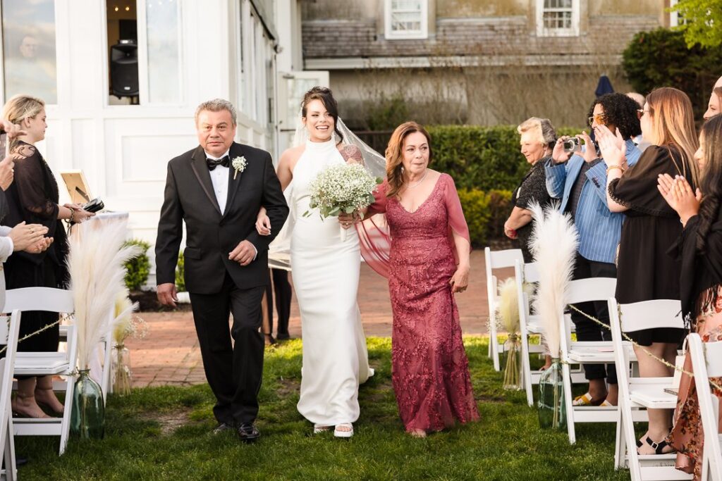 bride walking down aisle at Mansion at West Sayville with her parents