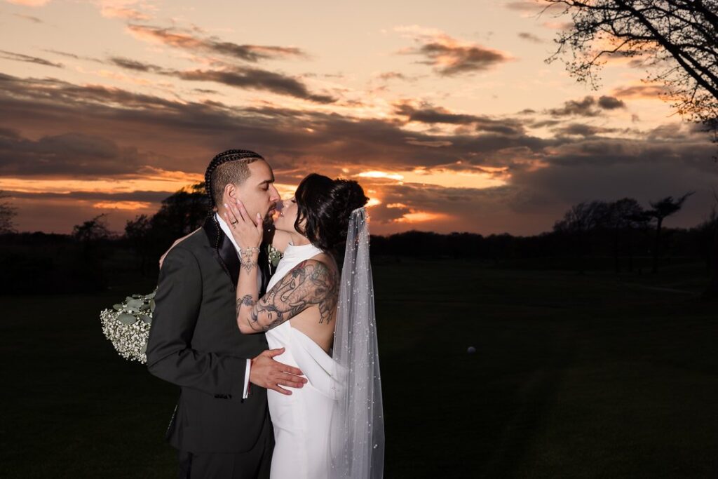 bride and groom kissing in front of dramatic sunset