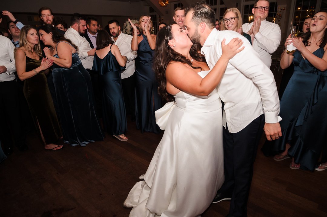 bride groom kissing surrounded by friends at heritage club reception