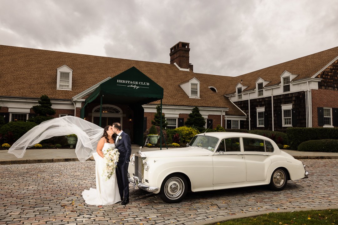 bride groom kissing in front of rolls Royce in front of heritage club Bethpage