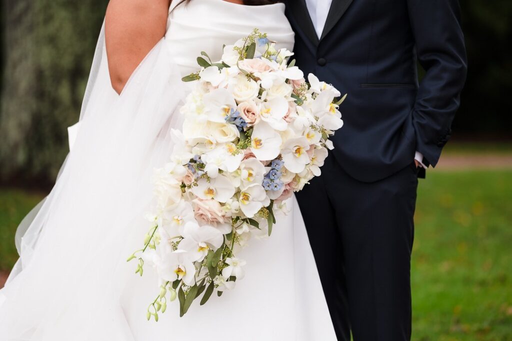 close of of brides bouquet with bride and groom in background