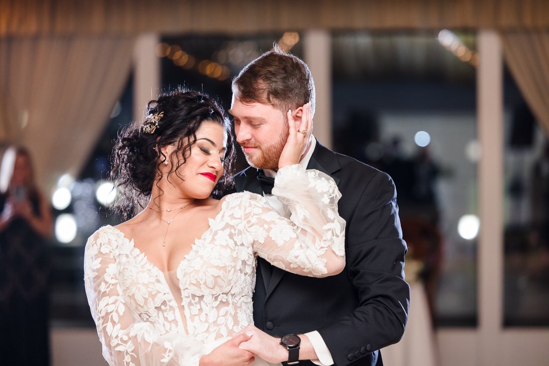 bride holding grooms face while dancing during reception