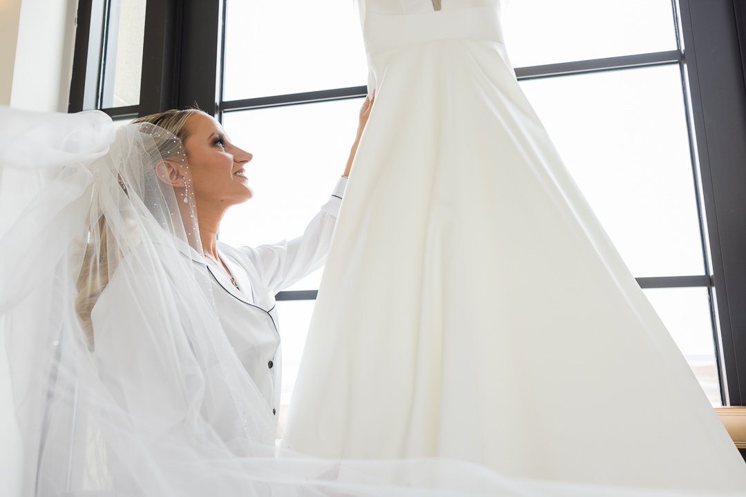 bride looking at wedding dress in window at Gatsby On The Ocean