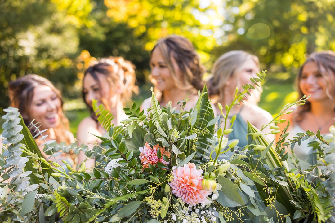 bride smiling at bridesmaids holding green bouquet