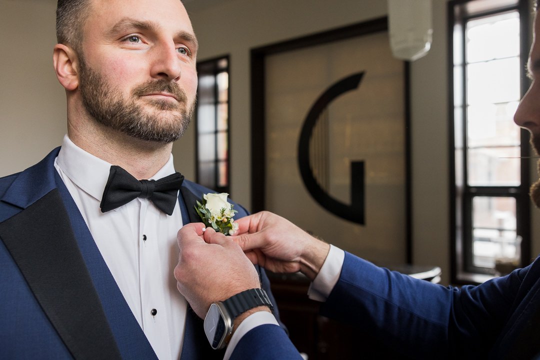 groom getting flower buttoned on lapel at Gatsby On The Ocean