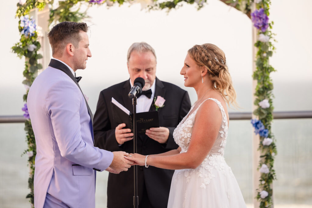 Bride and groom holding hands during the rooftop ceremony at the Allegria Hotel.