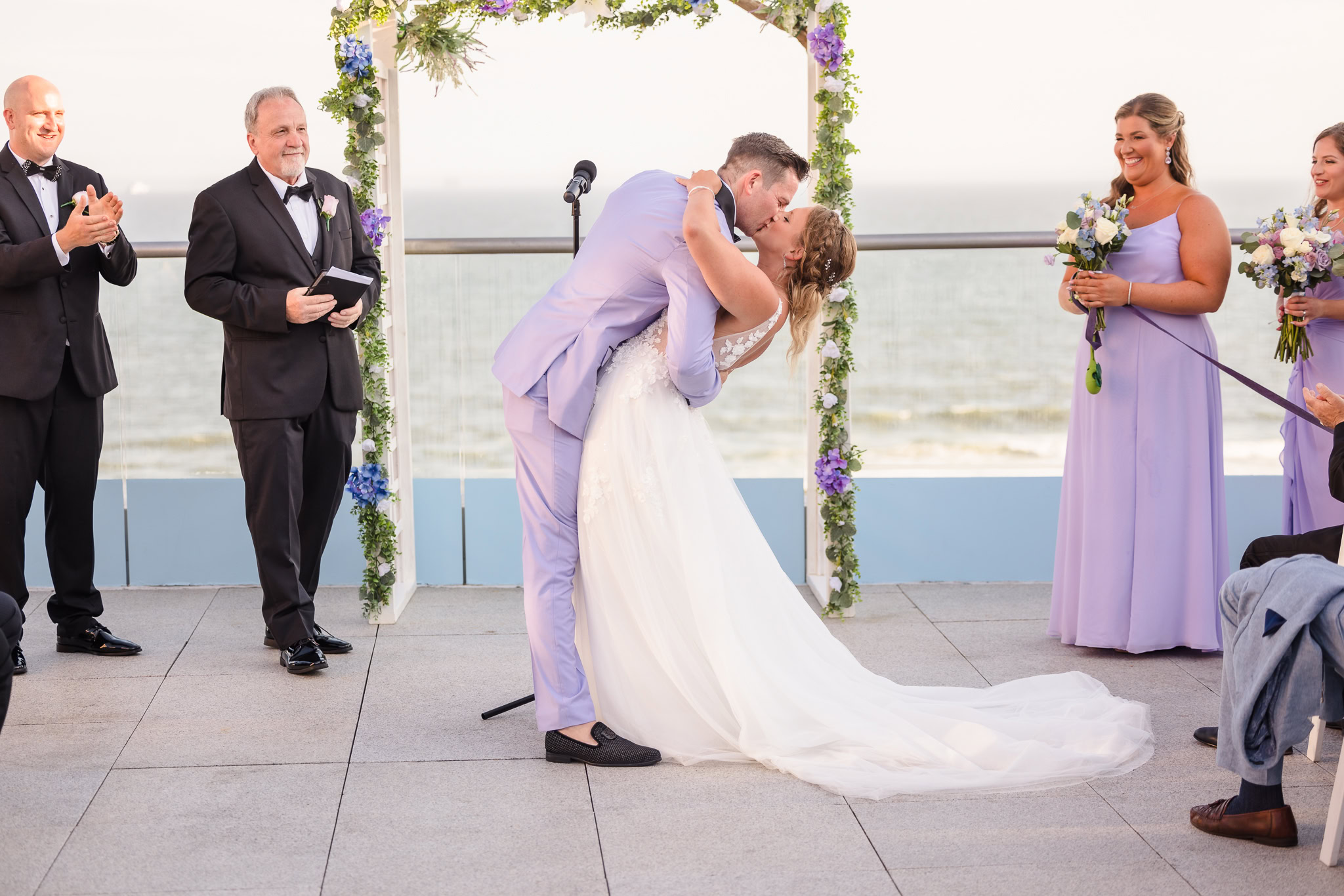 Bride and groom's first kiss on rooftop of Allegrai Hotel with beach in the background