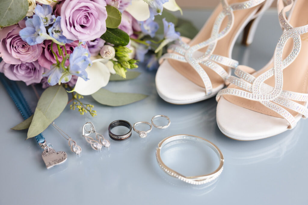 Rings, jewelry, flowers, and shoes laid out on a table