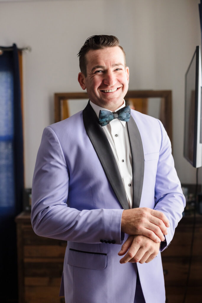 Groom smiling at the camera adjusting his watch