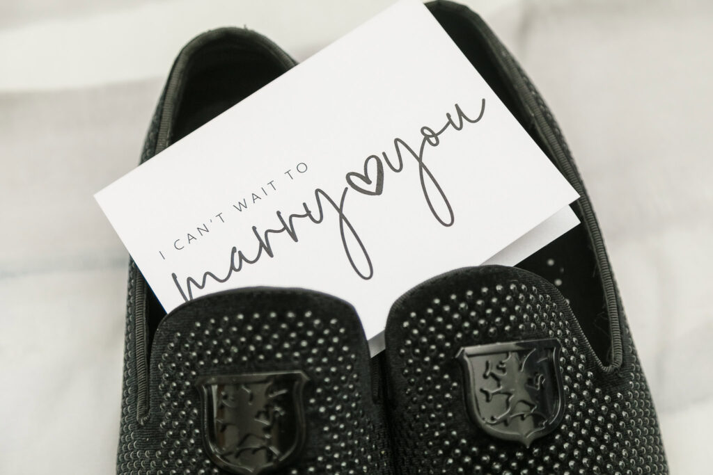 Two black shoes with a card on top that says "Marry You"