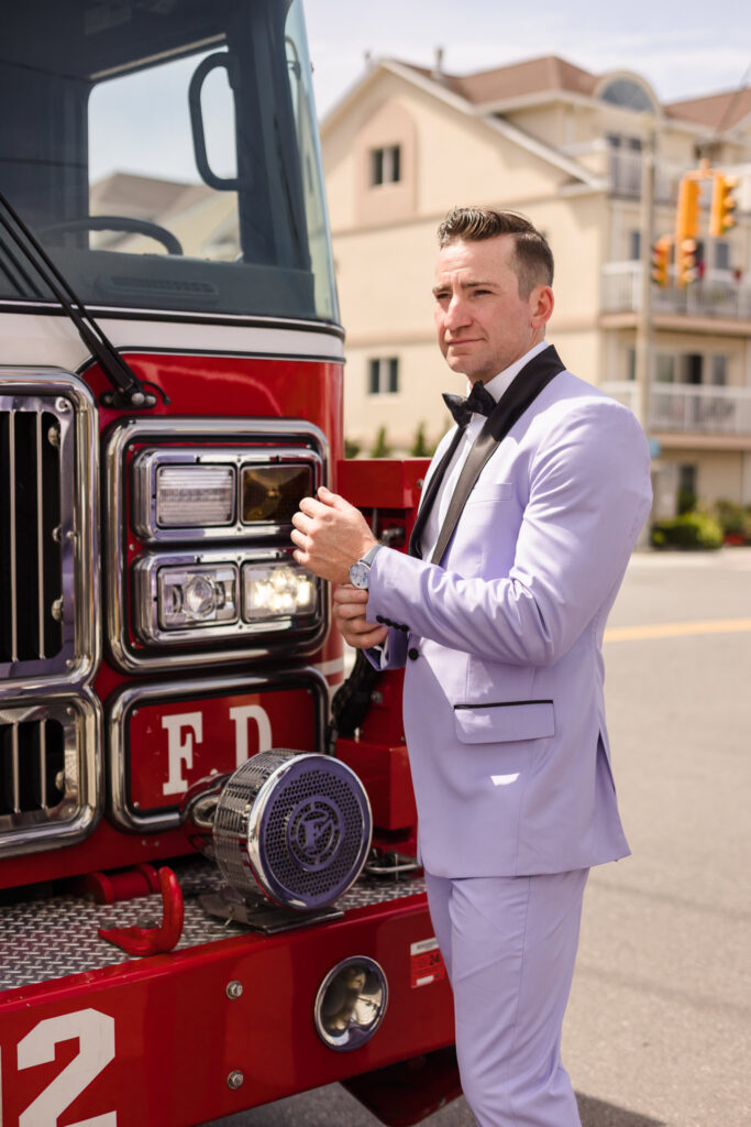 Groom adjusting his watch in front of fire truck.