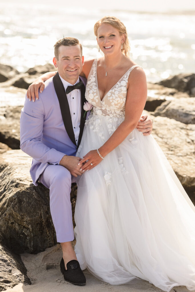 Bride and groom sitting on rocks at Long Beach