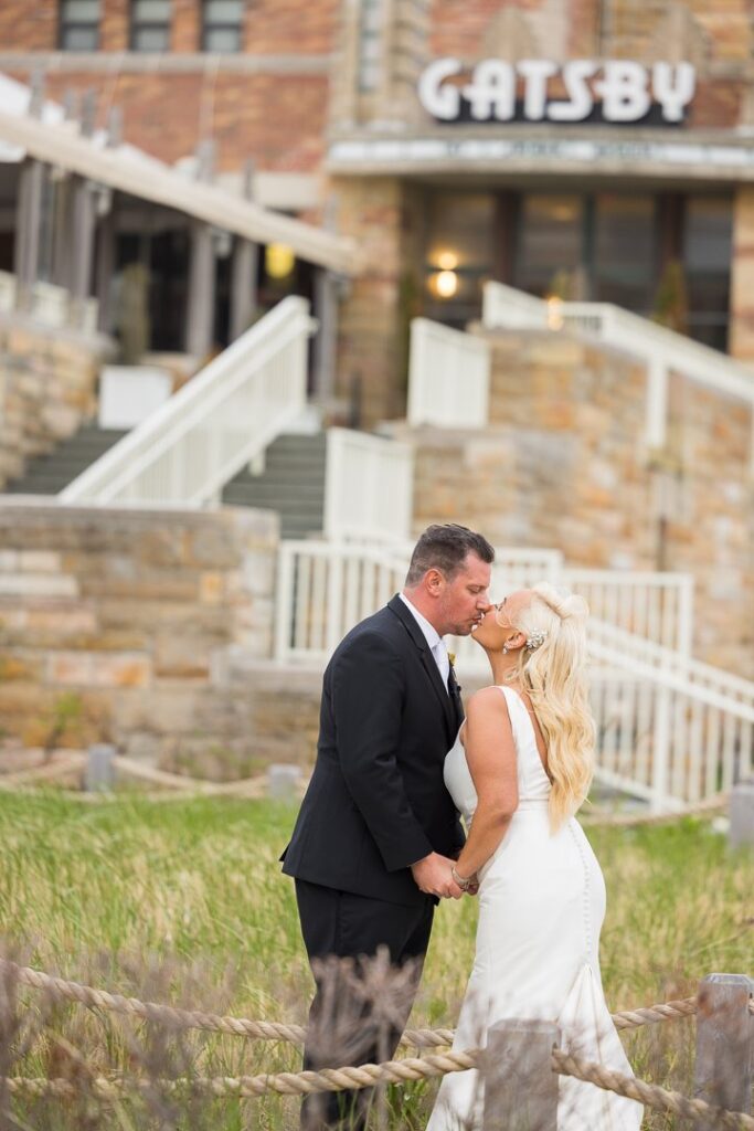 Bride and groom kissing in front of Gatsby on the Ocean