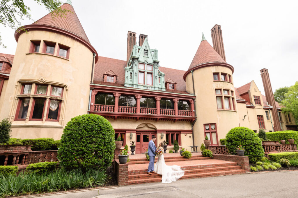 Bride and groom standing on the steps outside historic Coindre Hall with its distinctive towers and architecture behind them.