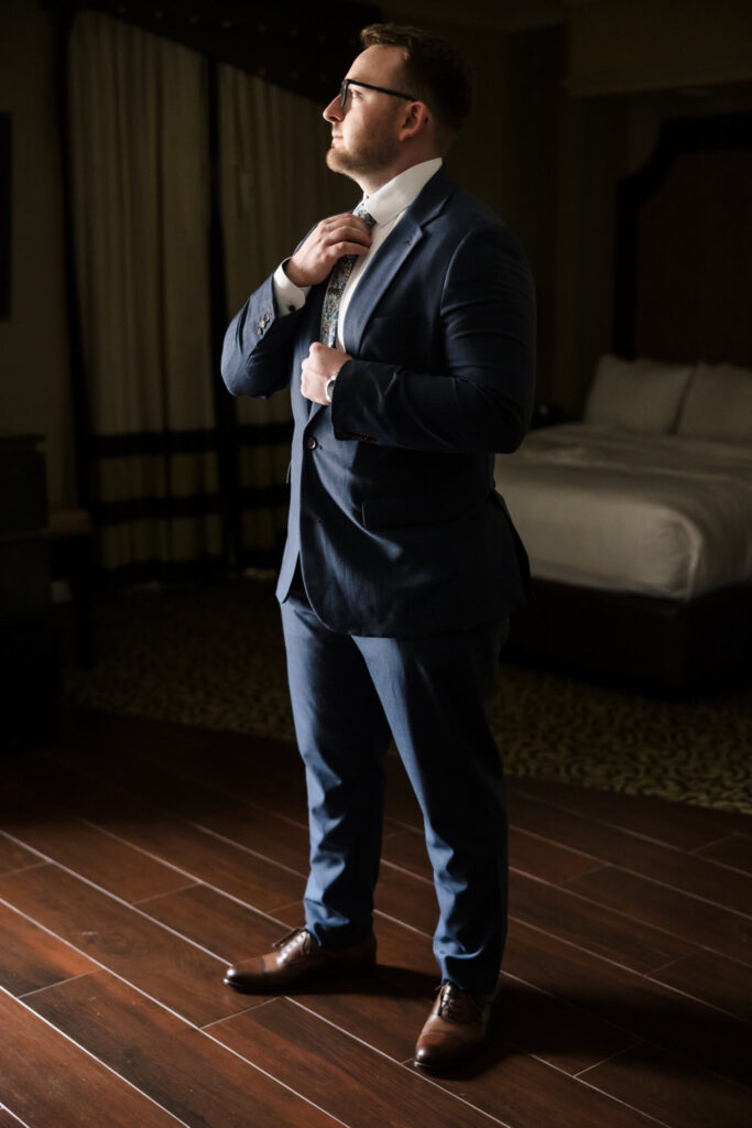 Full length image of groom adjusting his tie at Inn at Fox Hollow.