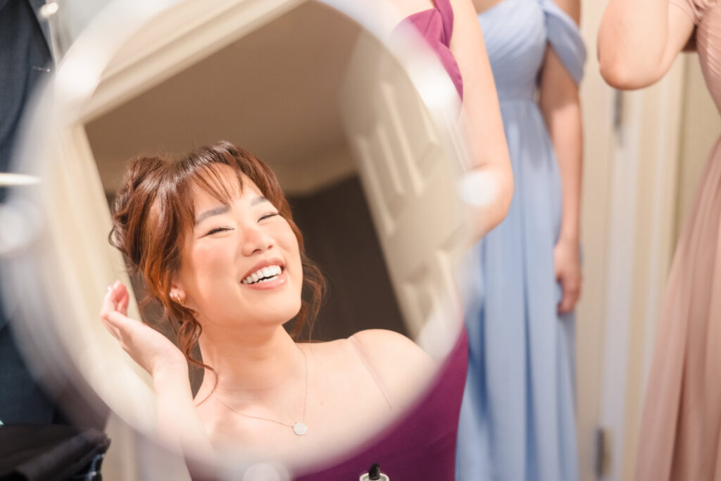 Bridesmaid looking into mirror while getting ready.