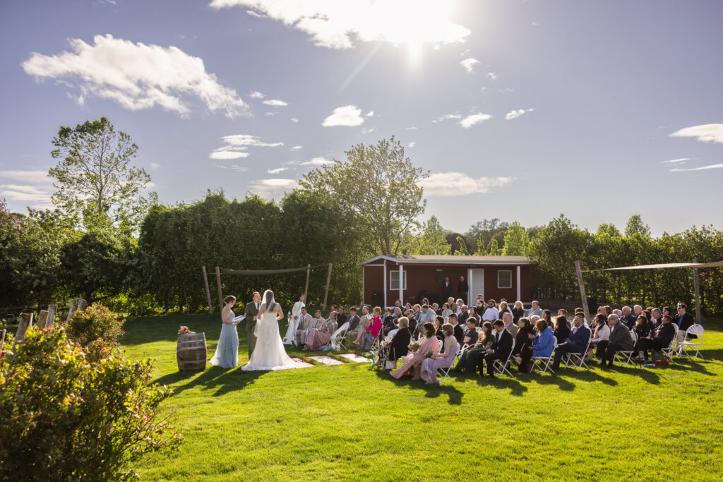Outdoor wedding ceremony at Baiting Hollow Farm Vineyard with guests seated on the lawn beneath a bright blue sky.