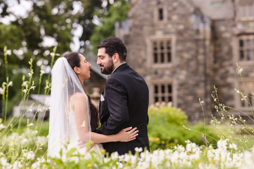 bride and groom looking at each other with Hempstead House in the back