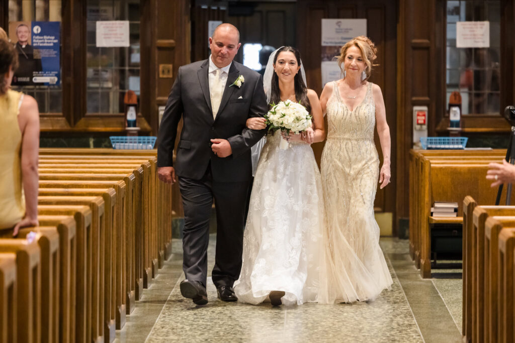 bride walking down the aisle with her mom and her dad