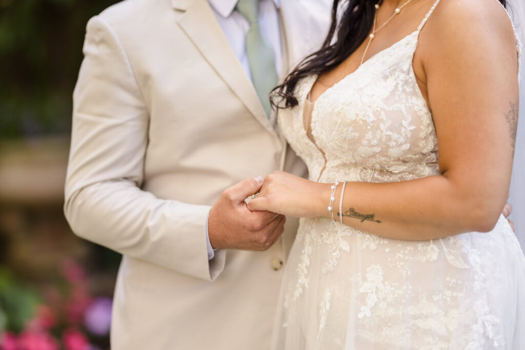 Close up of bride and groom holding hands.