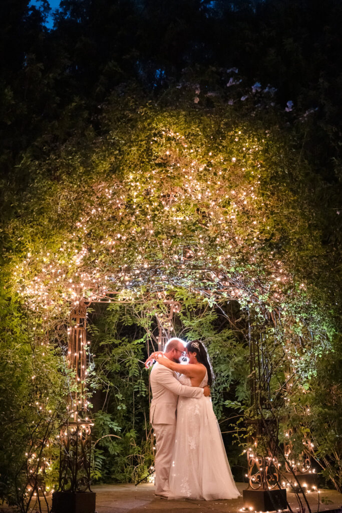 Couple in ceremony space at Majestic Gardens at night lit by tree lights.