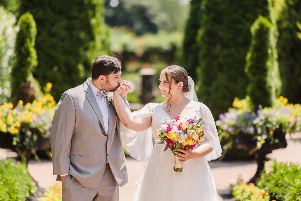 Groom kissing bride's hand in Larkfield Garden