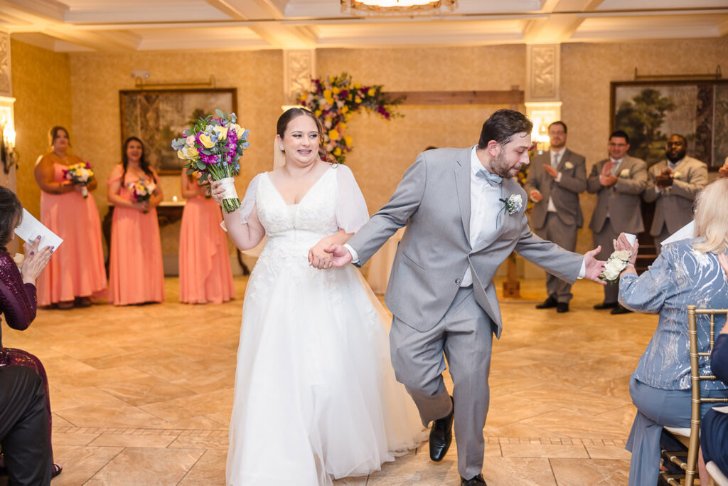 Groom giving a high five to a guest as bride and groom walk down the aisle after the ceremony.