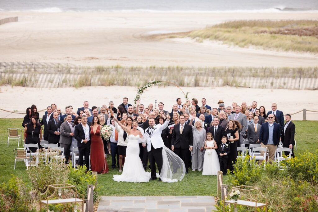 Bride, groom, and all guests in a large group photo in the ceremony space at Gatsby on the Ocean