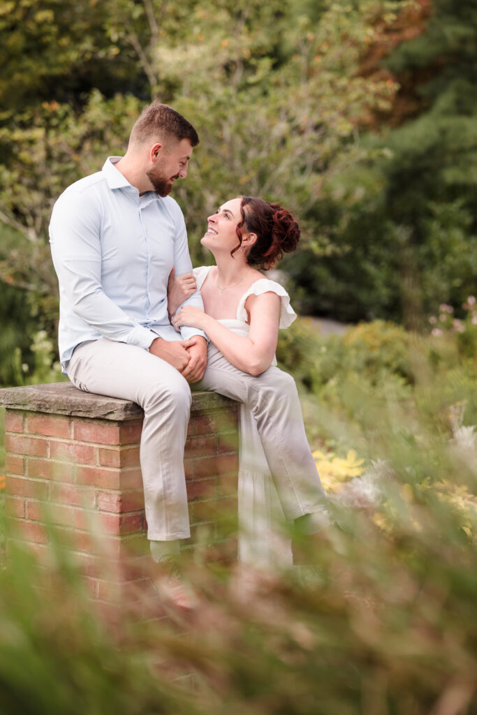 Man sitting on column and woman looking up at him at Planting Fields.