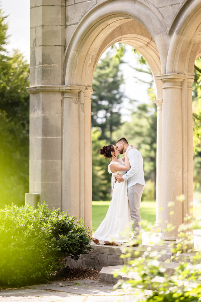 Woman and man kissing in archway at Planting Fields Arboretum.