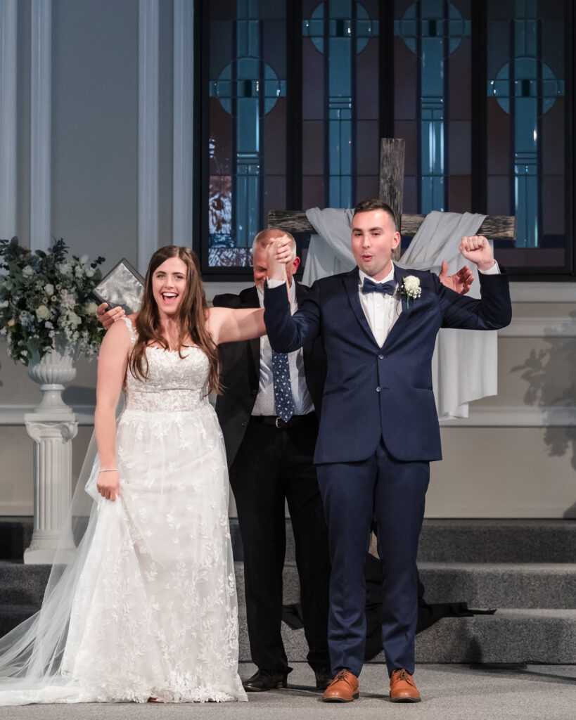 Bride and groom raising their hands to celebrate after the wedding ceremony.