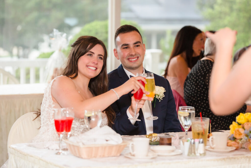 Bride and groom sitting at their sweetheart table and toasting at Rock Hill Country Club.