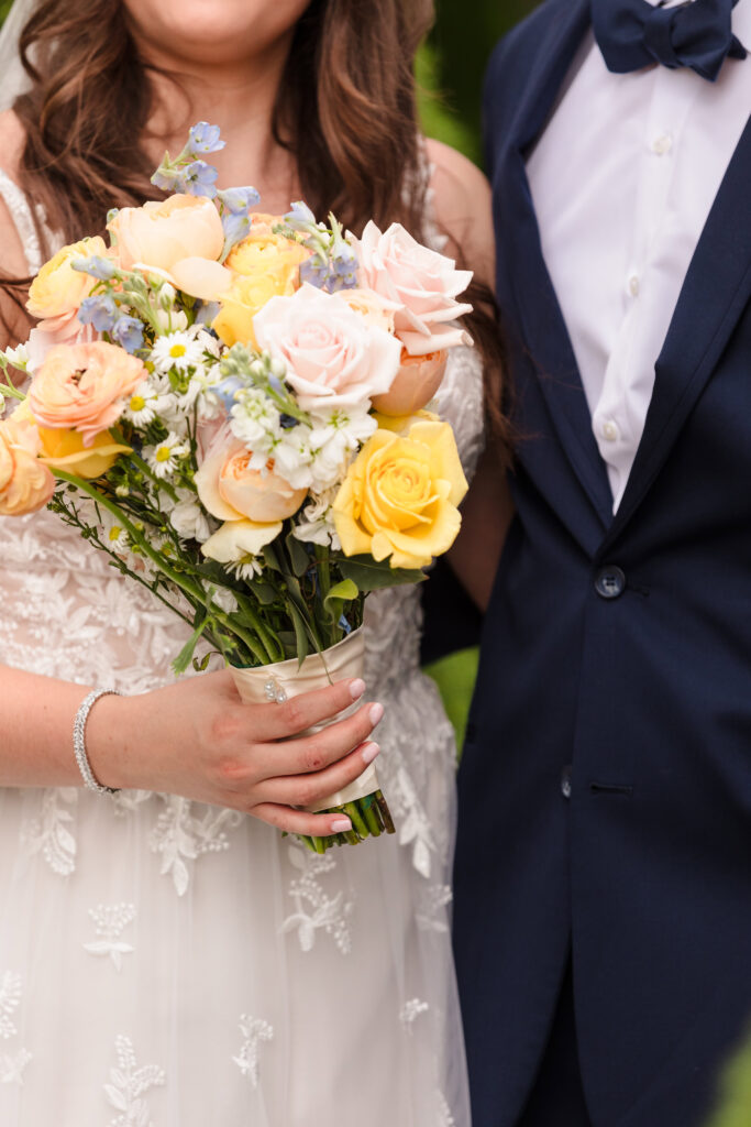 Close up of bride's flowers with bride and groom out of focus in the background.