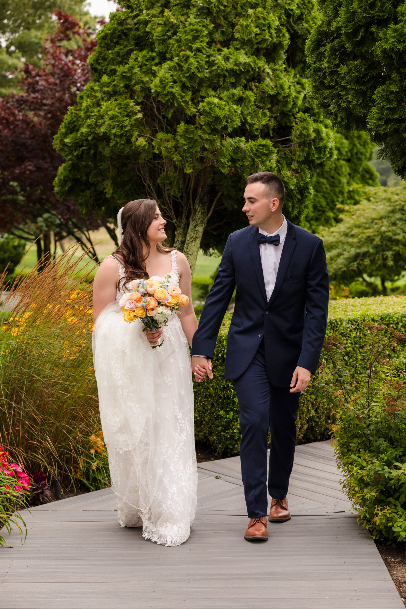 Bride and groom walking down a patch at Rock Hill Country Club talking with each other.