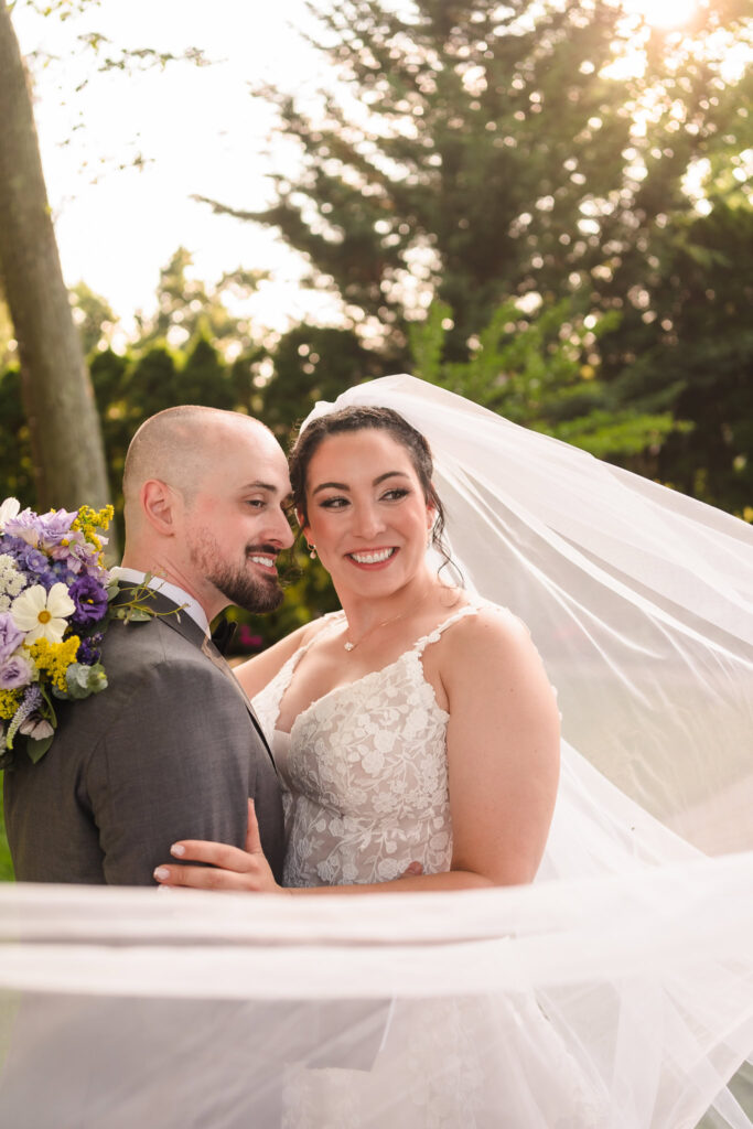 Bride and groom looking to camera right while the veil trails toward the camera.