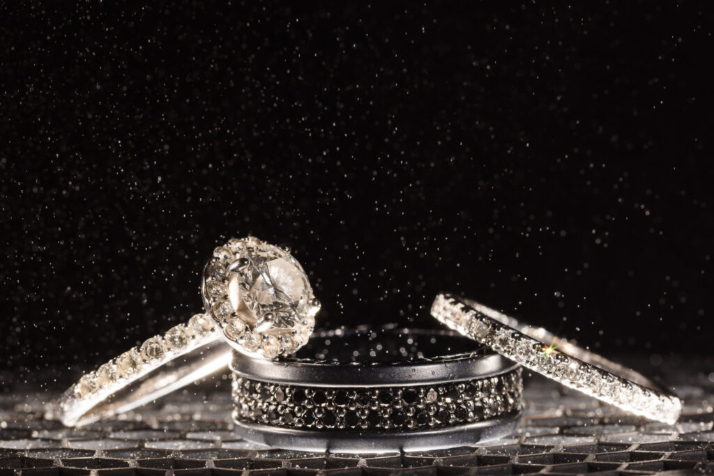 Close up shot of wedding rings and engagement rings with backlit water floating above.