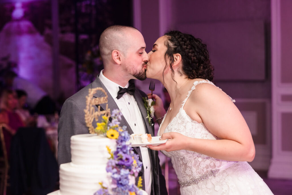 Bride and groom kissing over wedding cake at The Somerly at Fox Hollow.