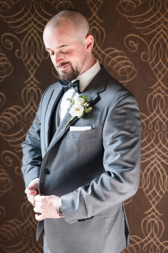 Groom buttoning suit at The Inn at Fox Hollow.