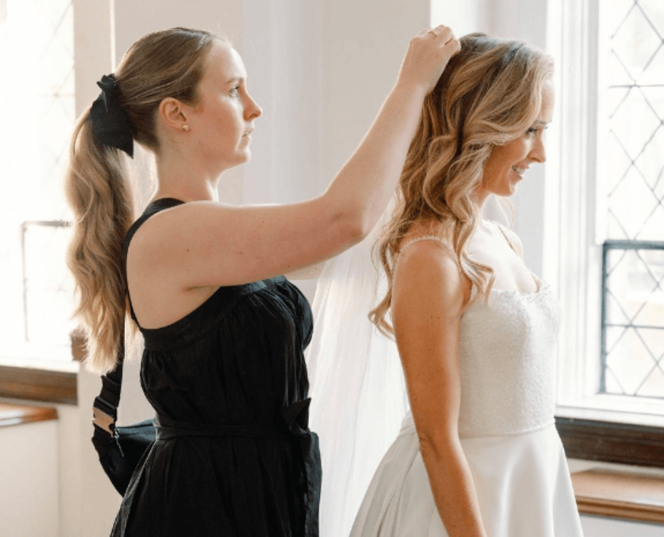 Wedding planner helps bride with hairpiece and veil. 