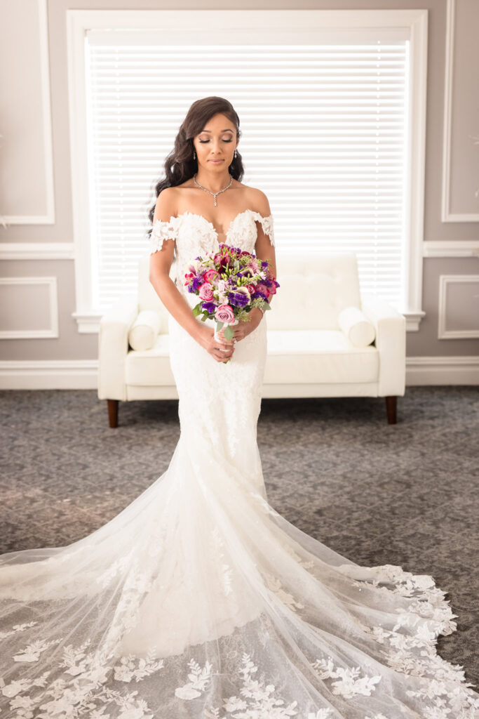 Bride in bridal suite at The Coral House. She is holding her flowers and looking down at them. 