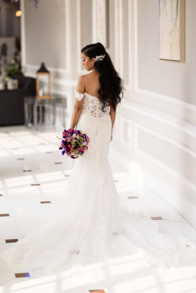 Bride from behind looking over her shoulder in the white hallway at The Coral House. 