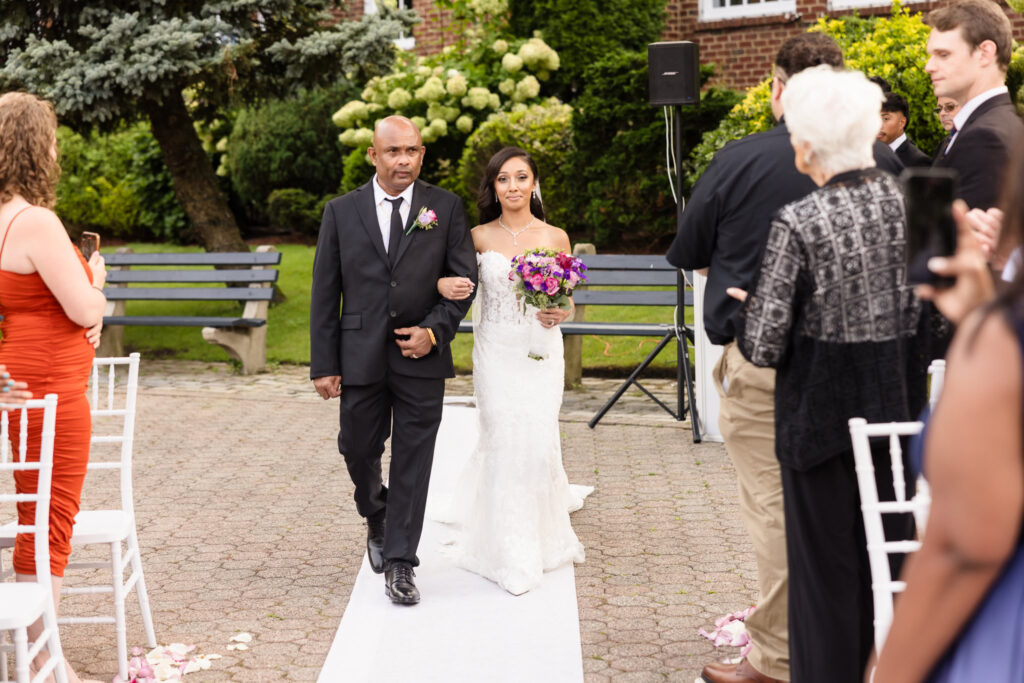 Bride and her father walking down the aisle at the outdoor ceremony at The Coral House.