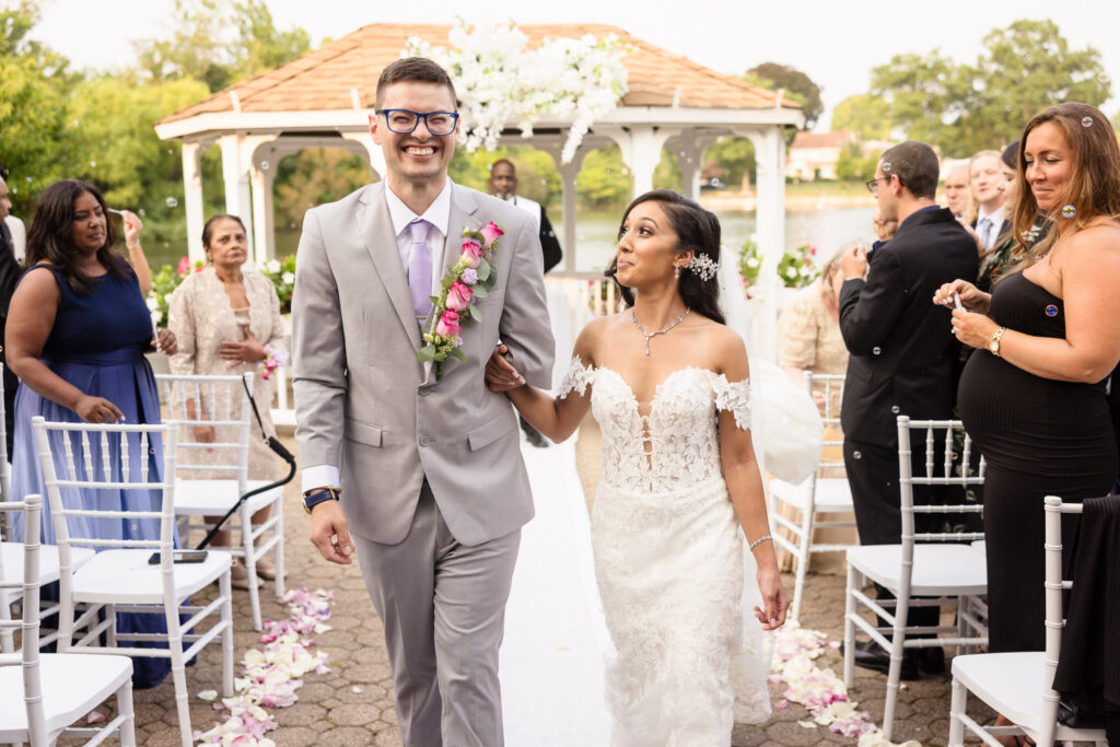 Bride and groom smiling while they walk down the aisle after the outdoor wedding ceremony at The Coral House.