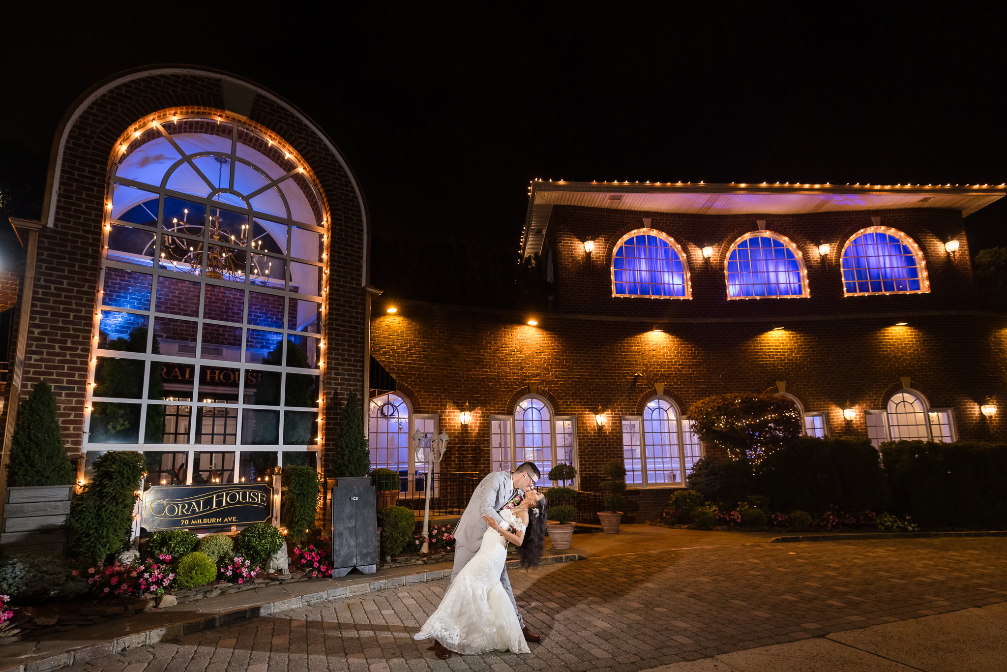 Couple in wedding attire dipping at night in front of The Coral House.