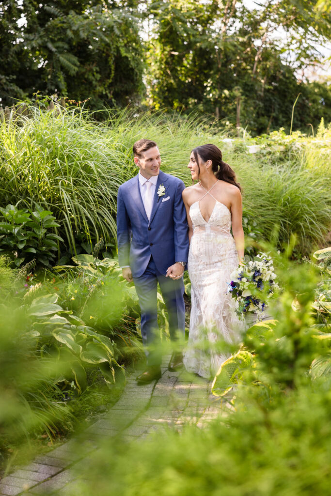 Bride and groom holding hands and looking at each other while walking at The Crescent Beach Club.