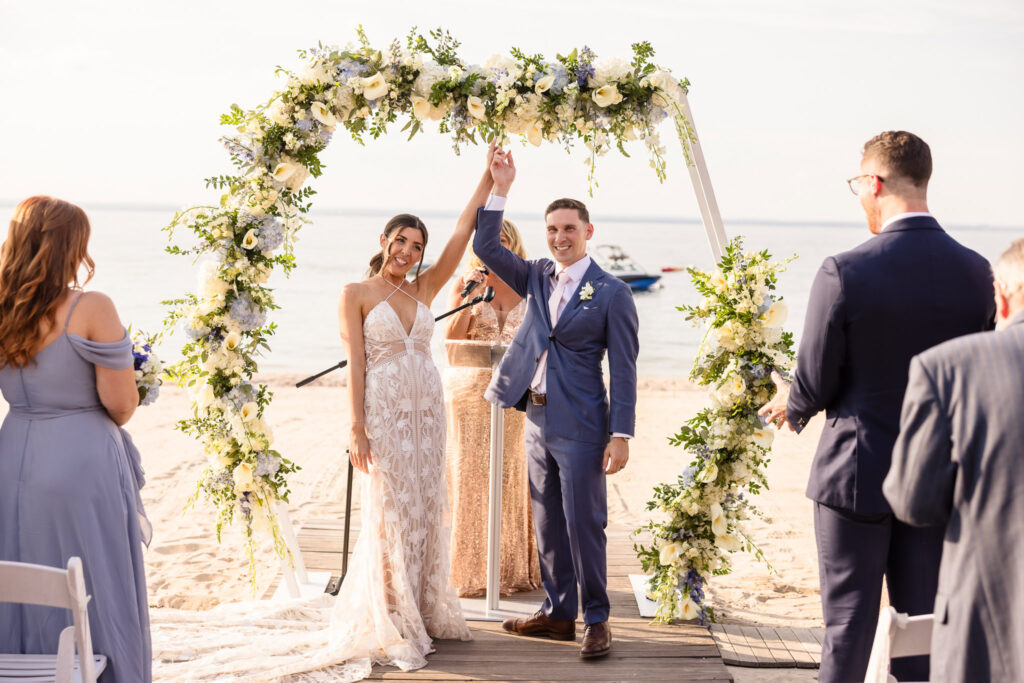 Bride and groom lifting their arms and celebrating right before they walked down the aisle at The Crescent Beach Club.