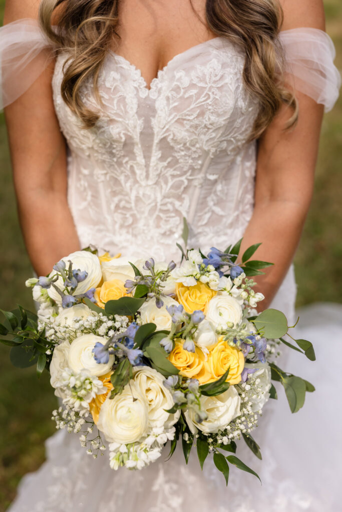 Brides yellow, green, blue, and white bouquet held by the bride.