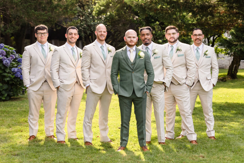 Groom and groomsmen posed and smiling while looking at the camera.